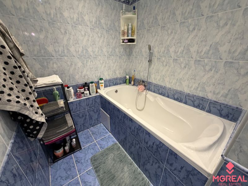 Badezimmer mit Badewanne und blauen Fliesen in einer 2-Zimmer-Wohnung.