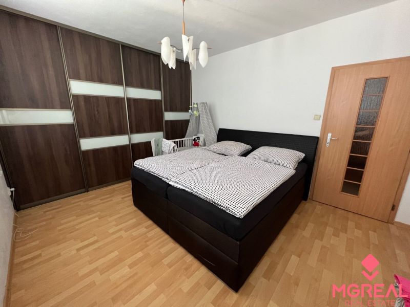 Schlafzimmer in einer 2-Zimmer-Wohnung mit großem Schrank und Boden in Holzoptik.