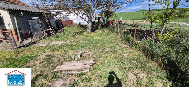 Ein Garten bei einem Einfamilienhaus im Dorf mit einem Baum und einem Zaun auf dem Land.