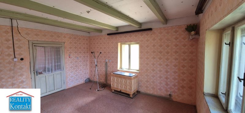 Ein Zimmer in einem Einfamilienhaus mit Retro-Tapeten, einem Heizkörper und einem Boden mit Holzdekor.