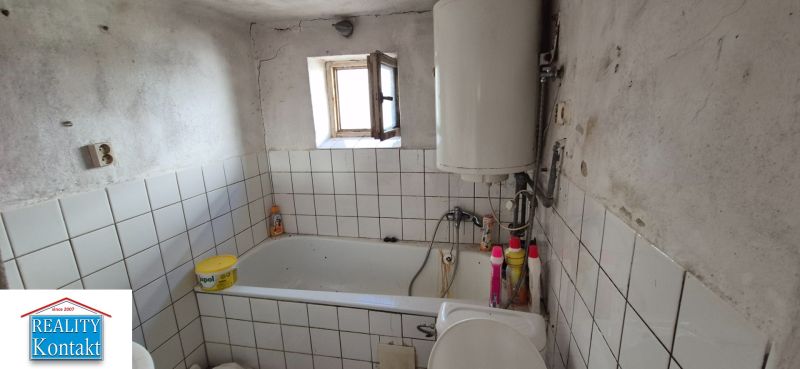 Badezimmer in einem Einfamilienhaus mit Fliesen, Badewanne und Boiler.