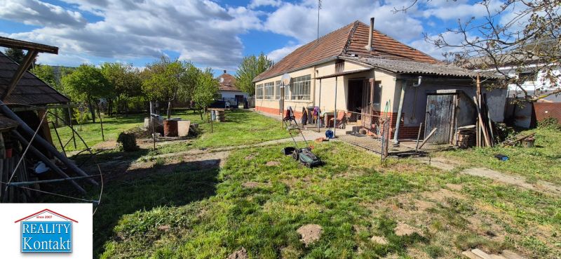 Žiadna Dedinka: Einfamilienhaus mit Garten und Anbau, mit einem Rasenmäher auf dem Rasen.
