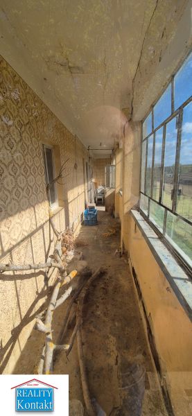 Im Einfamilienhaus befindet sich eine geschlossene Veranda mit älteren Fenstern und einer gemusterten Wand.