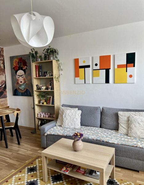 Wohnzimmer in einer 2-Zimmer-Wohnung mit Sofa, Tisch und Holzboden.