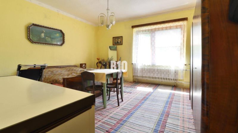 Ein Zimmer in einem Einfamilienhaus mit gelben Wänden, einem Tisch und einem Bett.