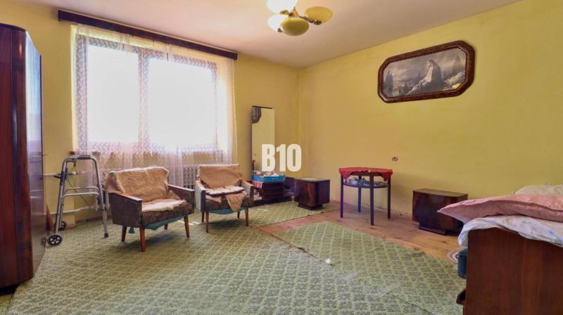 Ein Zimmer in einem Einfamilienhaus mit Sesseln, einem Tisch und Teppichboden.