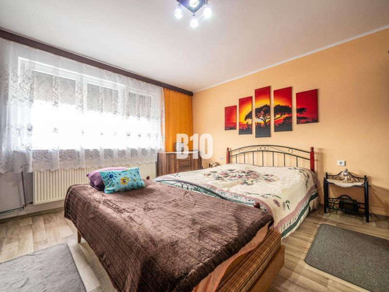 Schlafzimmer im Einfamilienhaus mit Bett, Holzboden und orangefarbenen Wänden.