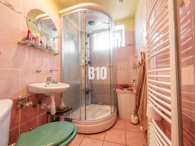 Badezimmer mit Dusche und rundem Spiegel in einem Einfamilienhaus.