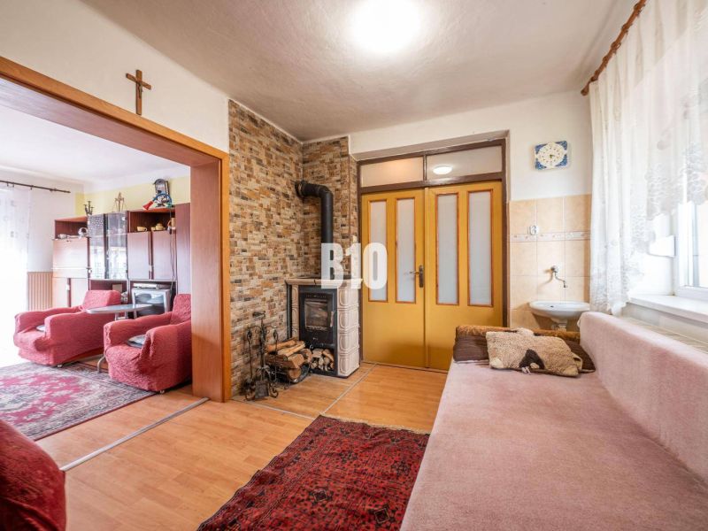 Wohnzimmer in einem Einfamilienhaus mit Kachelkamin und Boden mit Holzdekor.