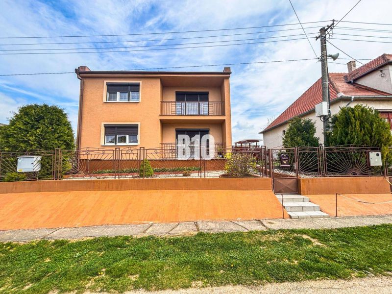 Ein Einfamilienhaus in Lukáčovce mit Garten und erhöhtem Eingang, umgeben von einem Zaun.