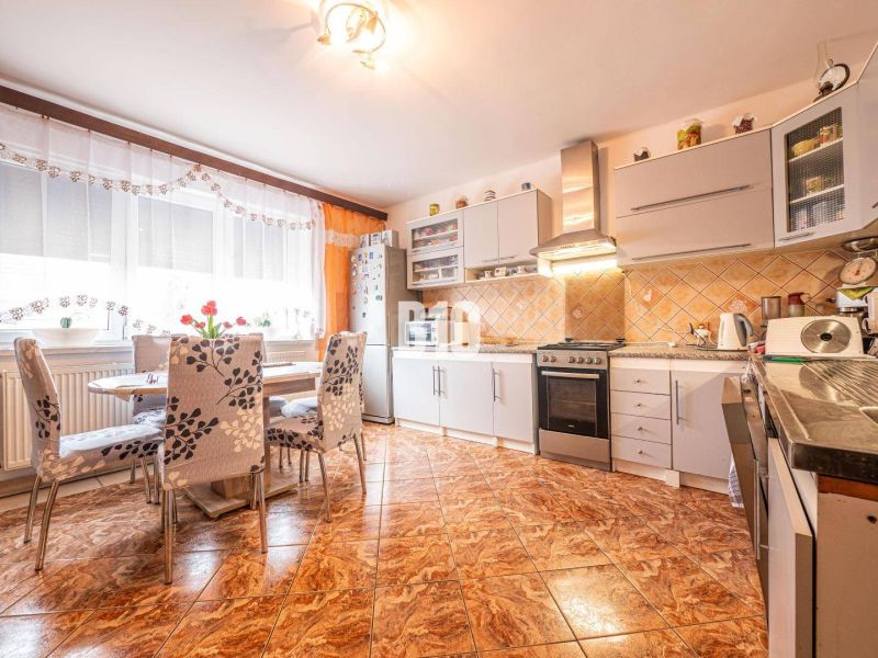 Küche in einem Einfamilienhaus mit Blumenstühlen und Fliesen in Holzoptik.