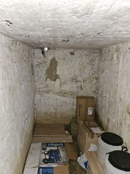 Lagerraum in einer Hütte mit verschiedenen Kisten und Plastikfässern auf dem Boden.