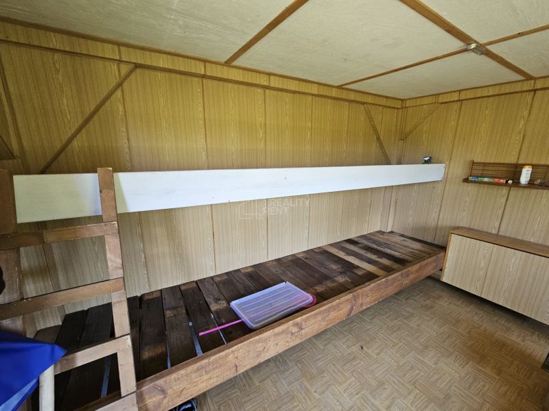 Das Innere der Hütte mit einem Etagenbett, einem Boden in Holzoptik und einer Holzwand.