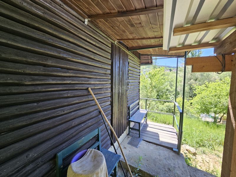 Eine Hütte in Budatín mit Holzverkleidung, Terrasse und Blick auf den grünen Garten.