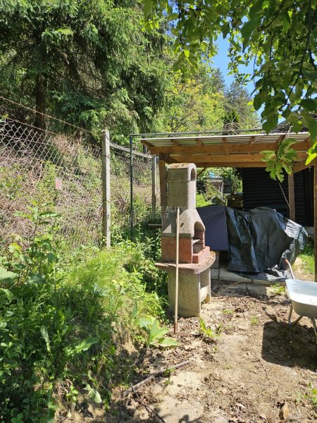 Ein Gartenkamin neben einer Hütte auf einem Waldweg in Budatín, umgeben von Grün.
