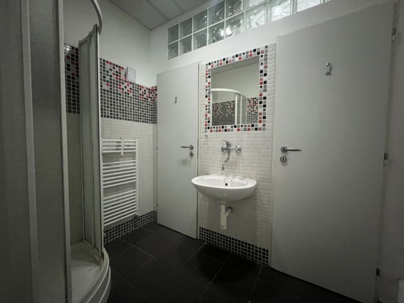 Ein Badezimmer mit Fliesen in Rot-Schwarz und einer Duschkabine in Produktionsräumen.