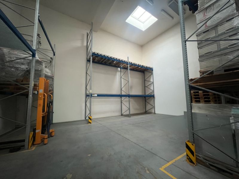 Lagerhallen und Hallen mit hohen Regalen und Dachfenstern, Betonboden.