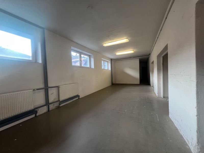 Langer Raum mit weißen Wänden, Fenstern und gusseisernen Heizkörpern in Lagern und Hallen.