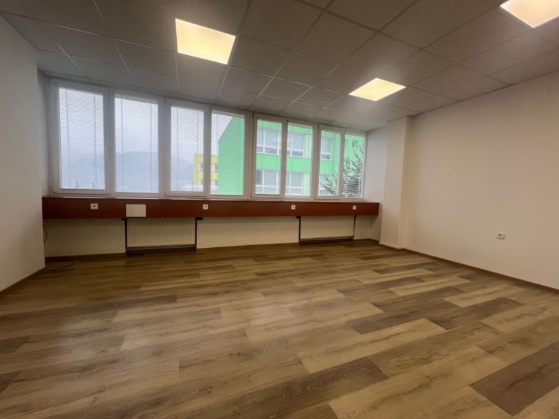Ein leeres Büro mit einem Holzboden und großen Fenstern.