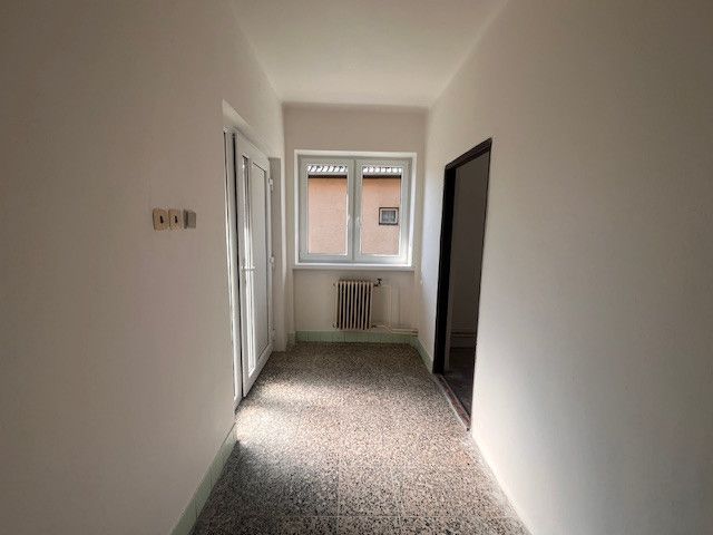 Das Innere eines Einfamilienhauses mit weißen Wänden, einem Heizkörper und einem großen Fenster.
