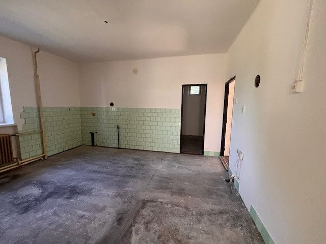Ein Zimmer in einem Einfamilienhaus mit unfertigem Boden und grünen Fliesen.