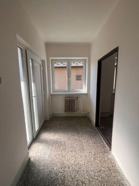 Ein schmaler Flur in einem Einfamilienhaus mit weißen Wänden und französischen Türen.
