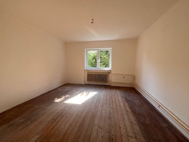 Innenraum eines Einfamilienhauses mit Holzboden und Fenster mit Blick ins Grüne.