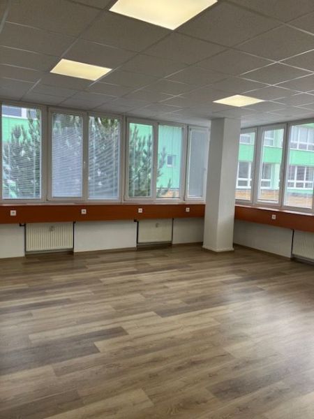 Büros mit Holzboden und großen Fenstern.