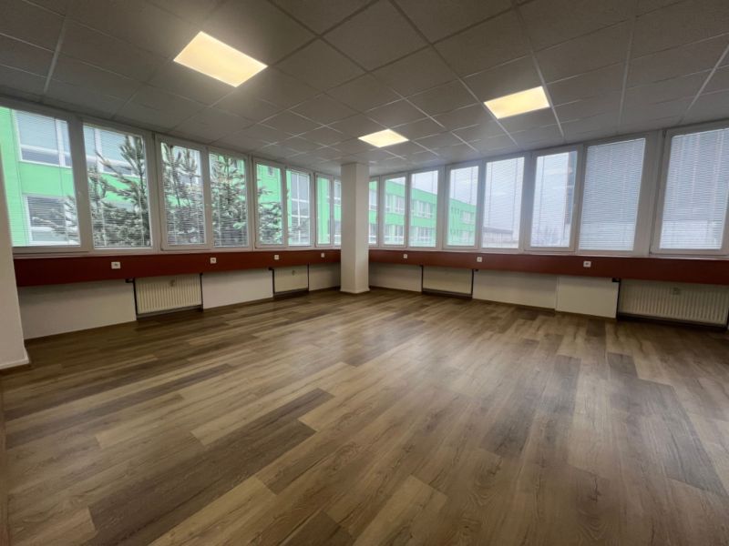 Große Büroräume mit Holzboden und großen Fenstern.