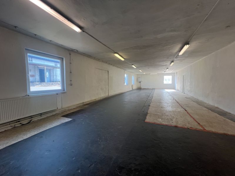 Innenfotografie zeigt einen leeren Raum mit schwarzem Boden und Fenstern, Lager und Hallen.