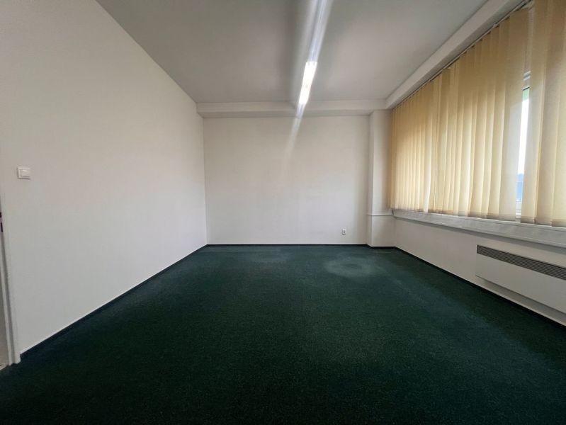 Büros mit Teppichboden und Vorhängen an großen Fenstern.