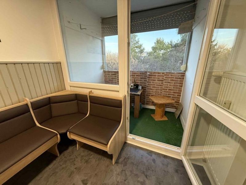 Helle Loggia einer 4-Zimmer-Wohnung mit Aussicht und Holzmöbeln.