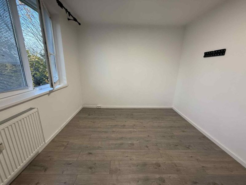 Helles Zimmer mit Holzboden und Heizkörper in einer Vierzimmerwohnung.
