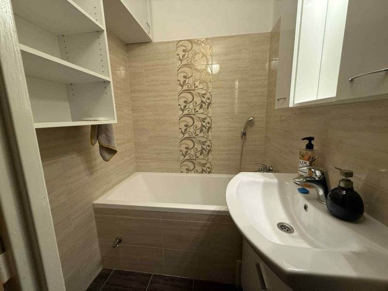 Badezimmer mit Badewanne in einer 4-Zimmer-Wohnung, mit Ablagefächern und dekorativen Fliesen.