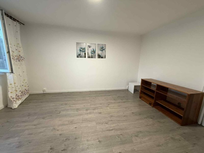 Wohnzimmer in einer 4-Zimmer-Wohnung mit Holzboden, Regal und Bildern an der Wand.