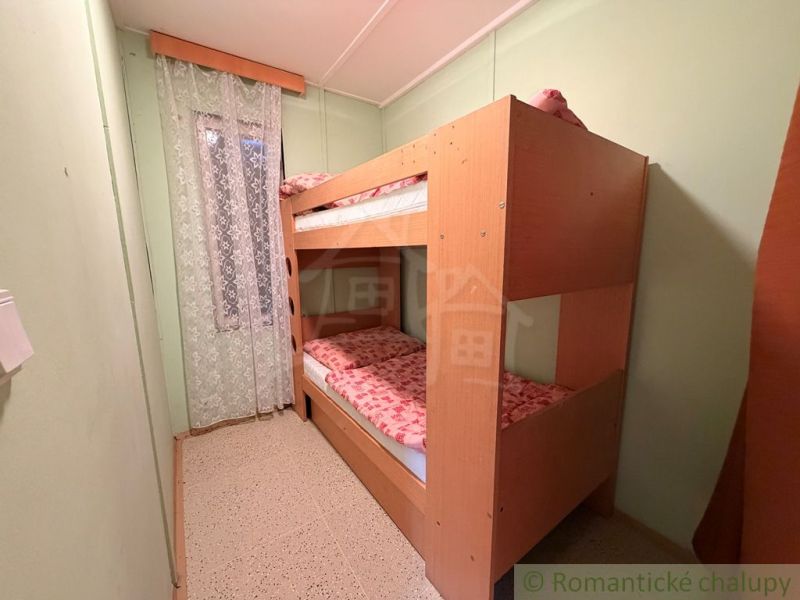 Etagenbett im Zimmer der Hütte mit einem Vorhang mit Blumenmuster.