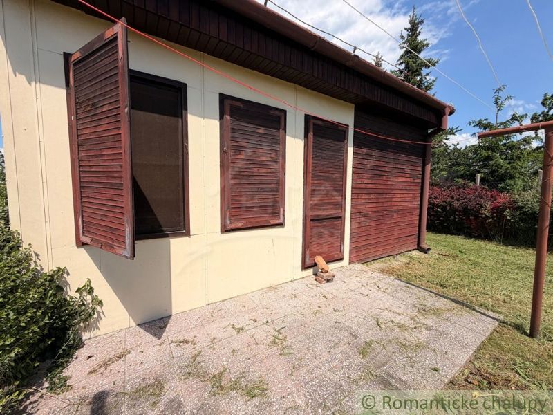 Ein Ferienhaus in Nové Zámky mit Holzläden und einem gepflegten Garten.