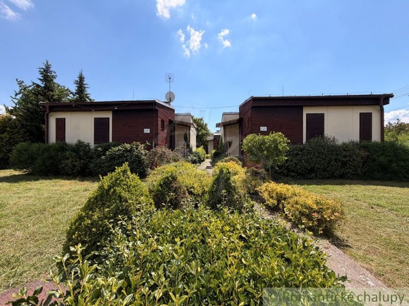 Ein Ferienhaus in Nové Zámky, umgeben von einem gepflegten Garten und Grünflächen, blauer Himmel.