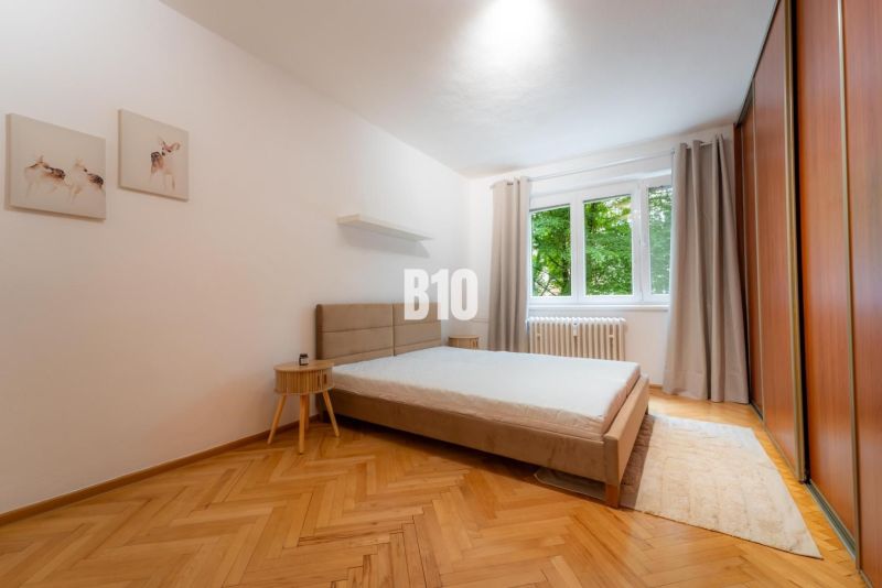 Schlafzimmer in einer 2-Zimmer-Wohnung mit großem Bett, Holzboden und Kleiderschrank.