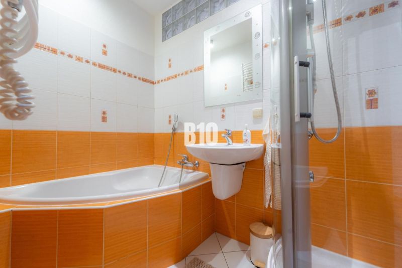 Badezimmer in einer 2-Zimmer-Wohnung mit dominierenden orangefarbenen Fliesen und einer Badewanne.