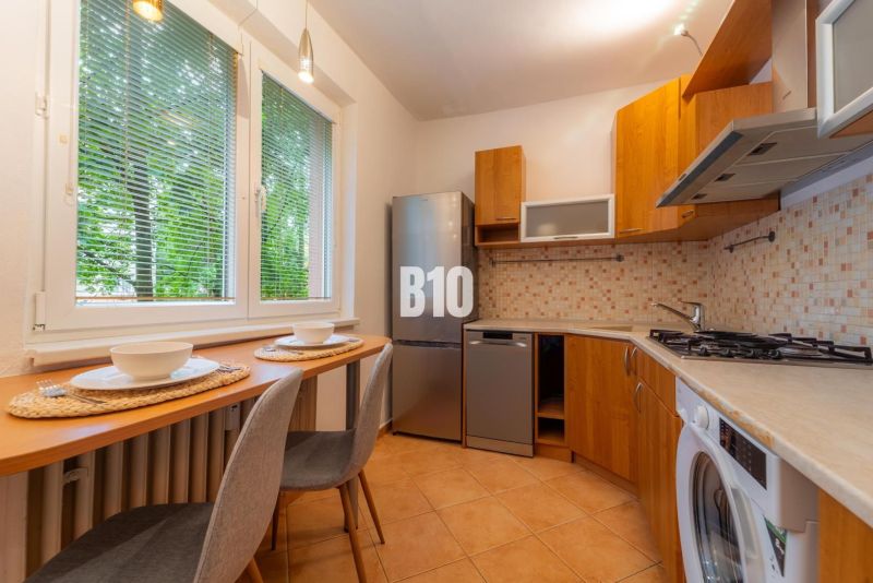 Küche in einer 2-Zimmer-Wohnung mit Holzelementen und Geräten, wunderschön beleuchtet.