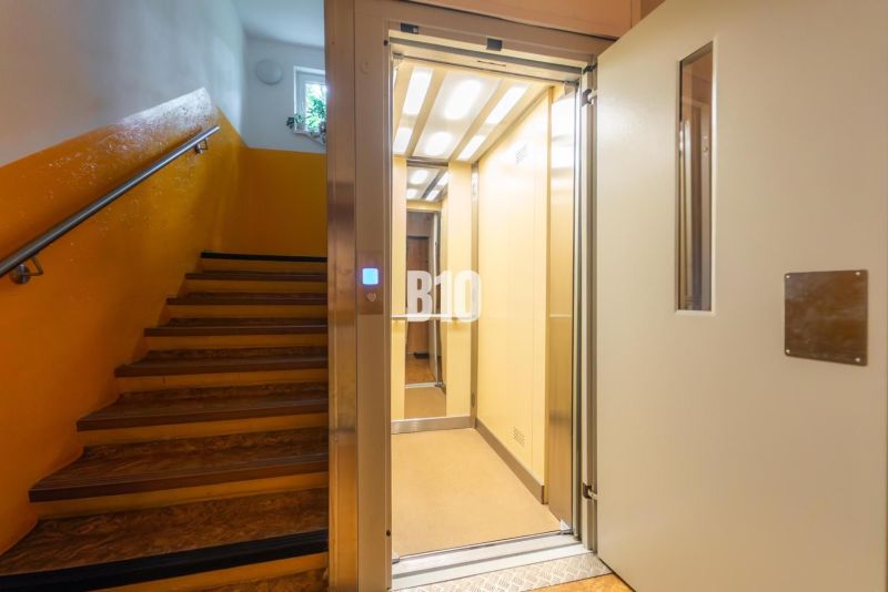 Das Treppenhaus eines Gebäudes mit einem offenen Aufzug und gelben Wänden in einem Wohnhaus.