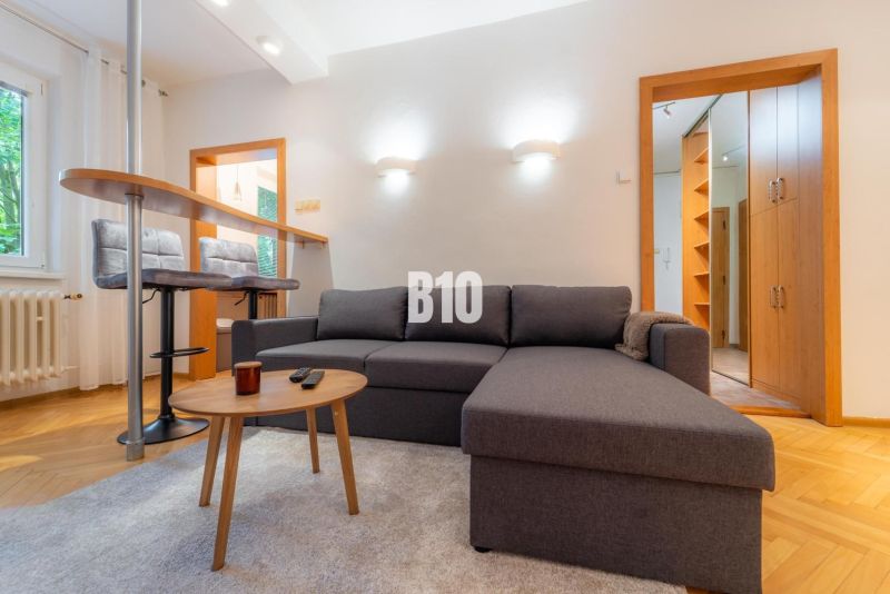 Wohnzimmer mit Sofa, Bartresen und Holzboden in einer Zweizimmerwohnung.