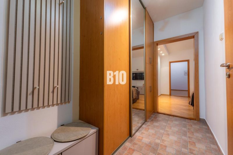 Eingangsflur mit Garderobe, Spiegelschrank und Holzboden in einer 2-Zimmer-Wohnung.