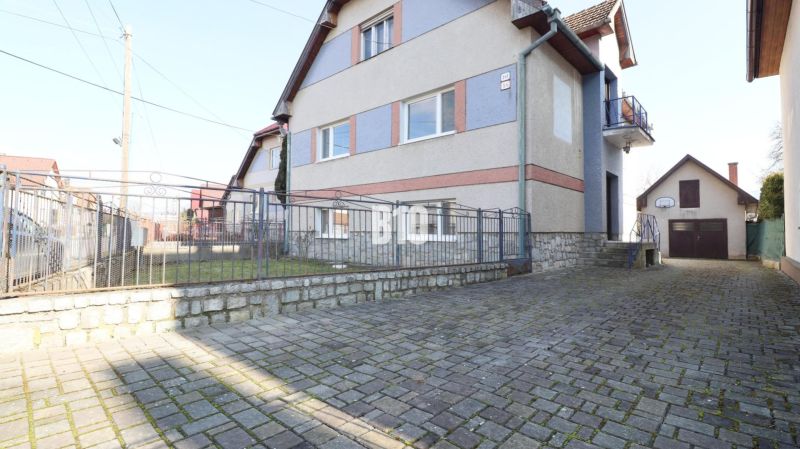 Ein Einfamilienhaus in Turany mit Hof und gepflasterter Zufahrtsstraße.