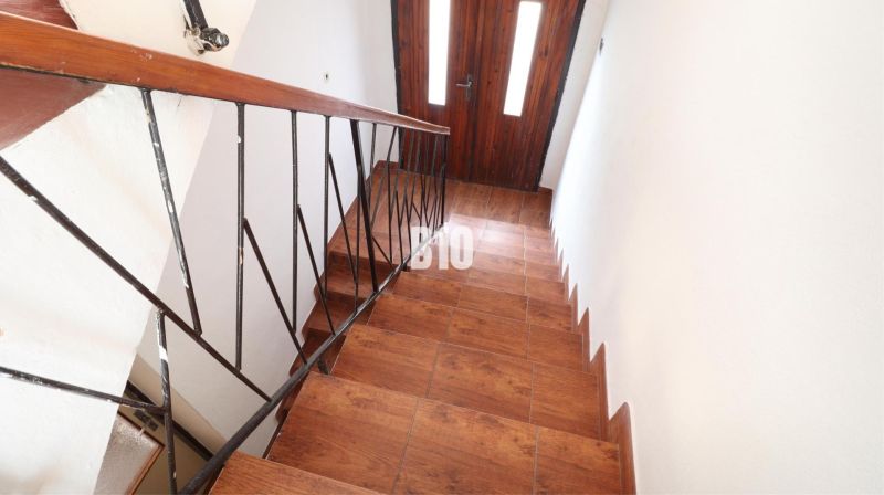 Eine Treppe in einem Einfamilienhaus mit einem Boden in Holzoptik und einem Geländer aus Metall.