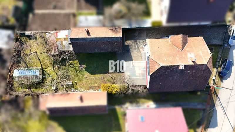 Ein Blick auf das Einfamilienhaus in Turany mit einem weitläufigen Garten und einem Gewächshaus.