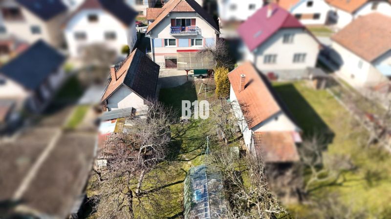 Ein Einfamilienhaus in Turany mit einem großen Hof und Anbauten, umgeben von einem Garten.