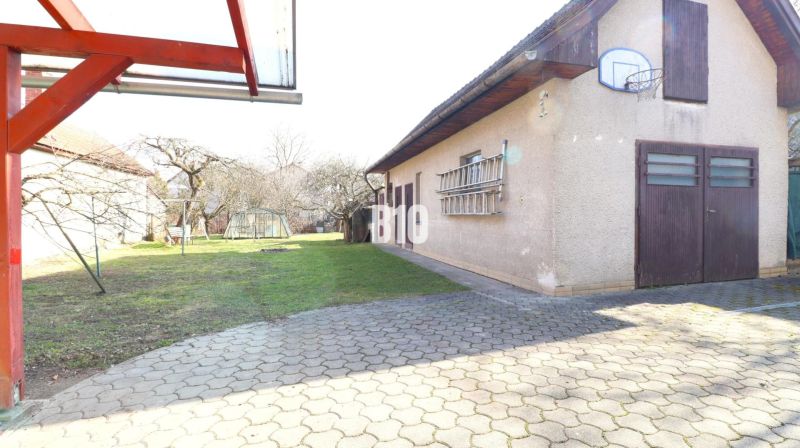 Der Hof beim Einfamilienhaus in Turany mit einem Basketballkorb und einem Gartengewächshaus.