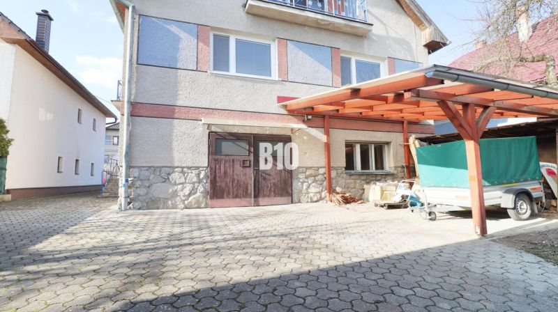 Ein Einfamilienhaus in Turany mit befestigter Zufahrtsfläche und einem Carport.